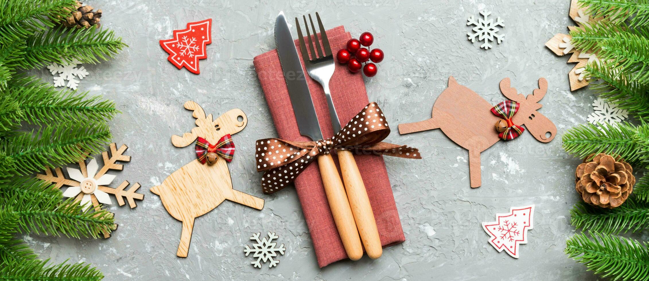 Top view Banner of flatware tied up with ribbon on napkin on cement background. Close up of christmas decorations and reindeer. New Year holiday concept photo