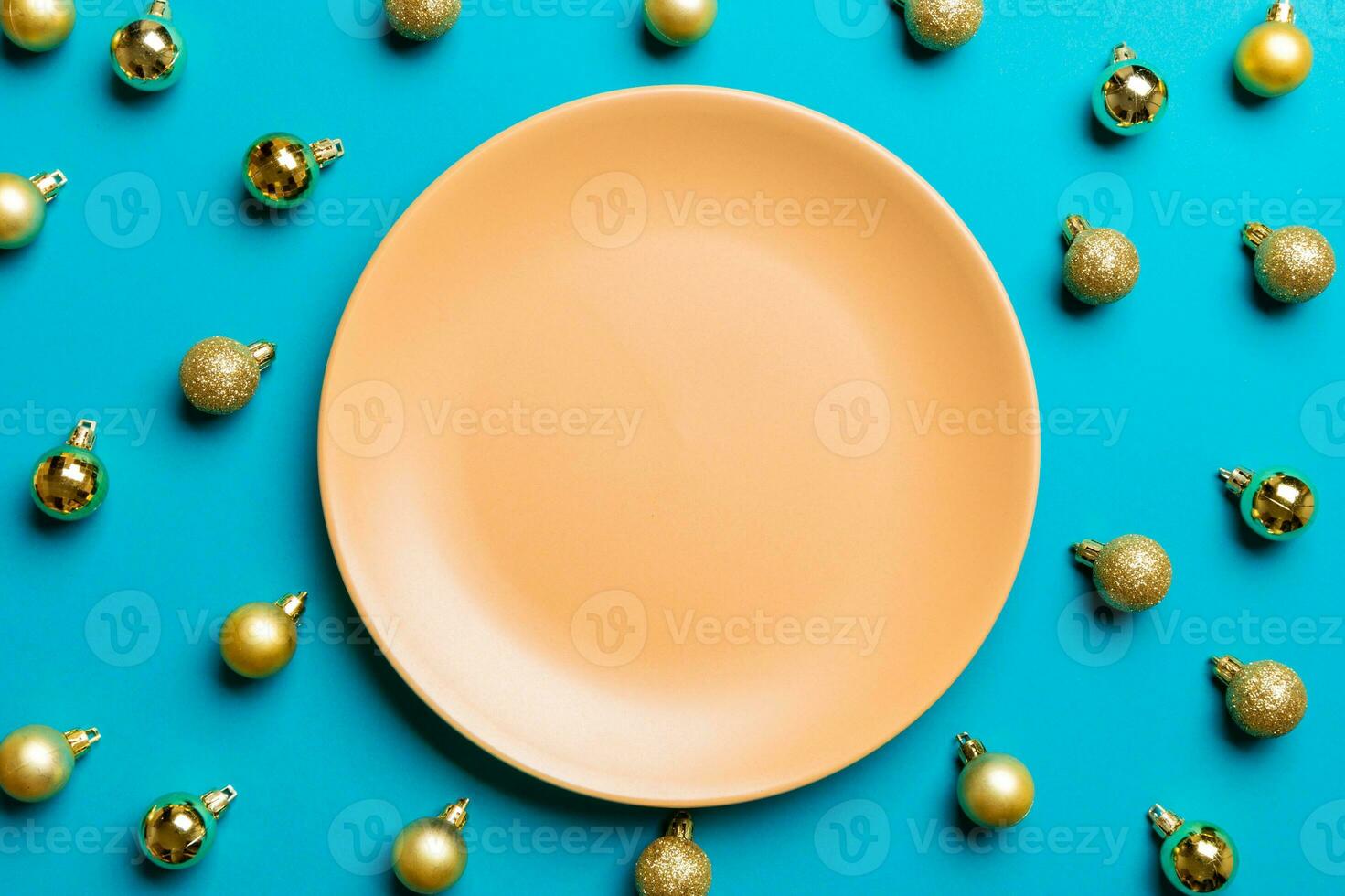 Top view of festive plate with golden baubles on colorful background. Christmas decorations and toys. New Year advent concept photo
