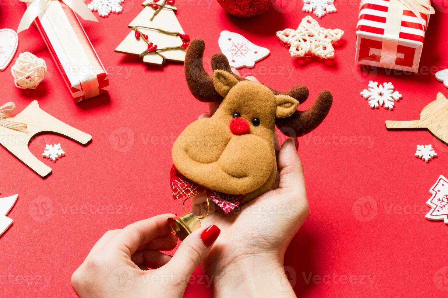 Top view of reindeer in female hands on red background. Christmas decorations. New Year holiday concept photo