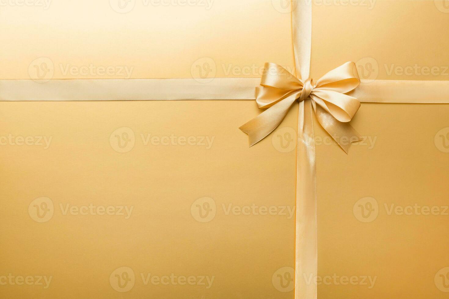 Top view of gold ribbon rolled and yellowbow isolated on colored background. Flat lay with copy space photo