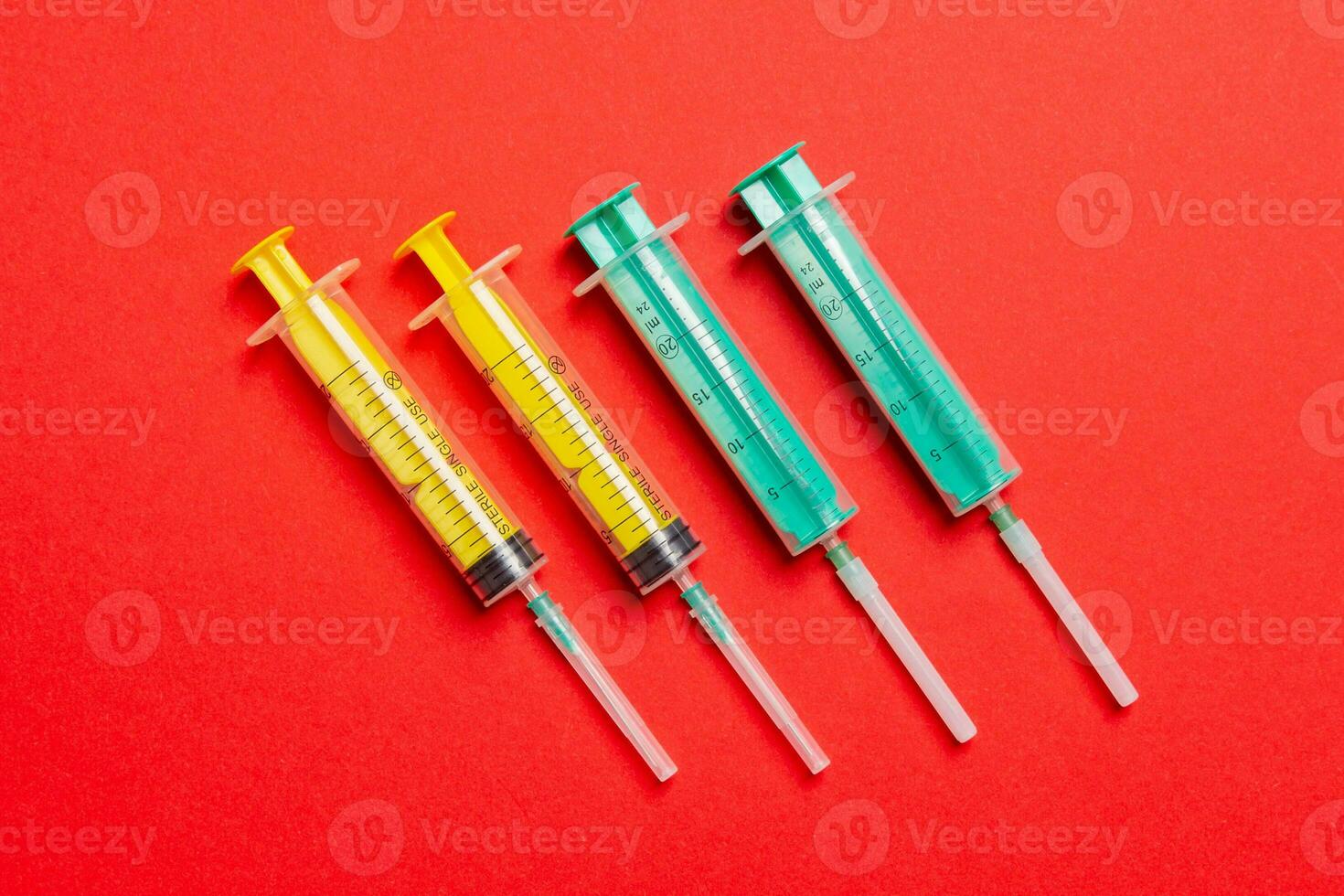 Top view of medical syringes with needles at red background with copy space. Injection treatment concept photo