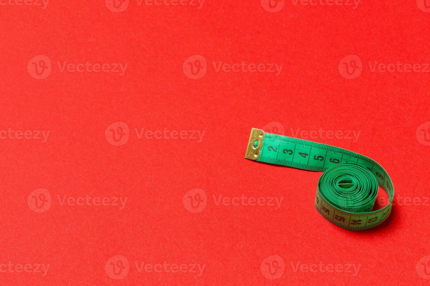 Top view of curled measuring tape as a sewing accessory on red background. Tailor concept with copy space photo