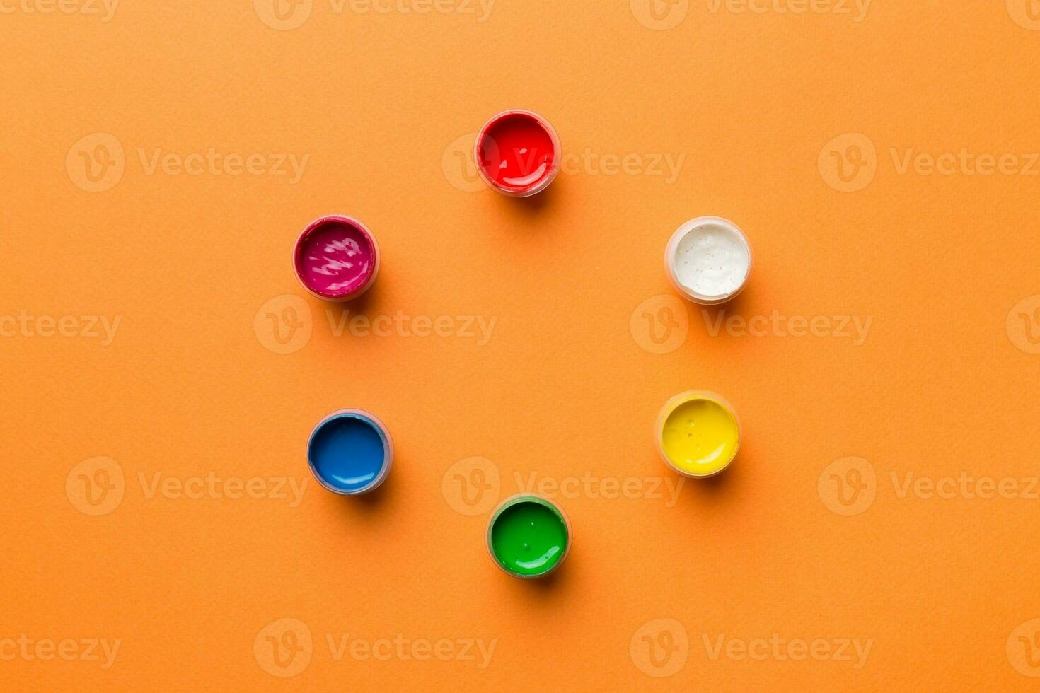 jars with gouache of different colors on Colored background. hobby painting. Top view with empty space. workplace for creativity. home teaching concept drawing photo