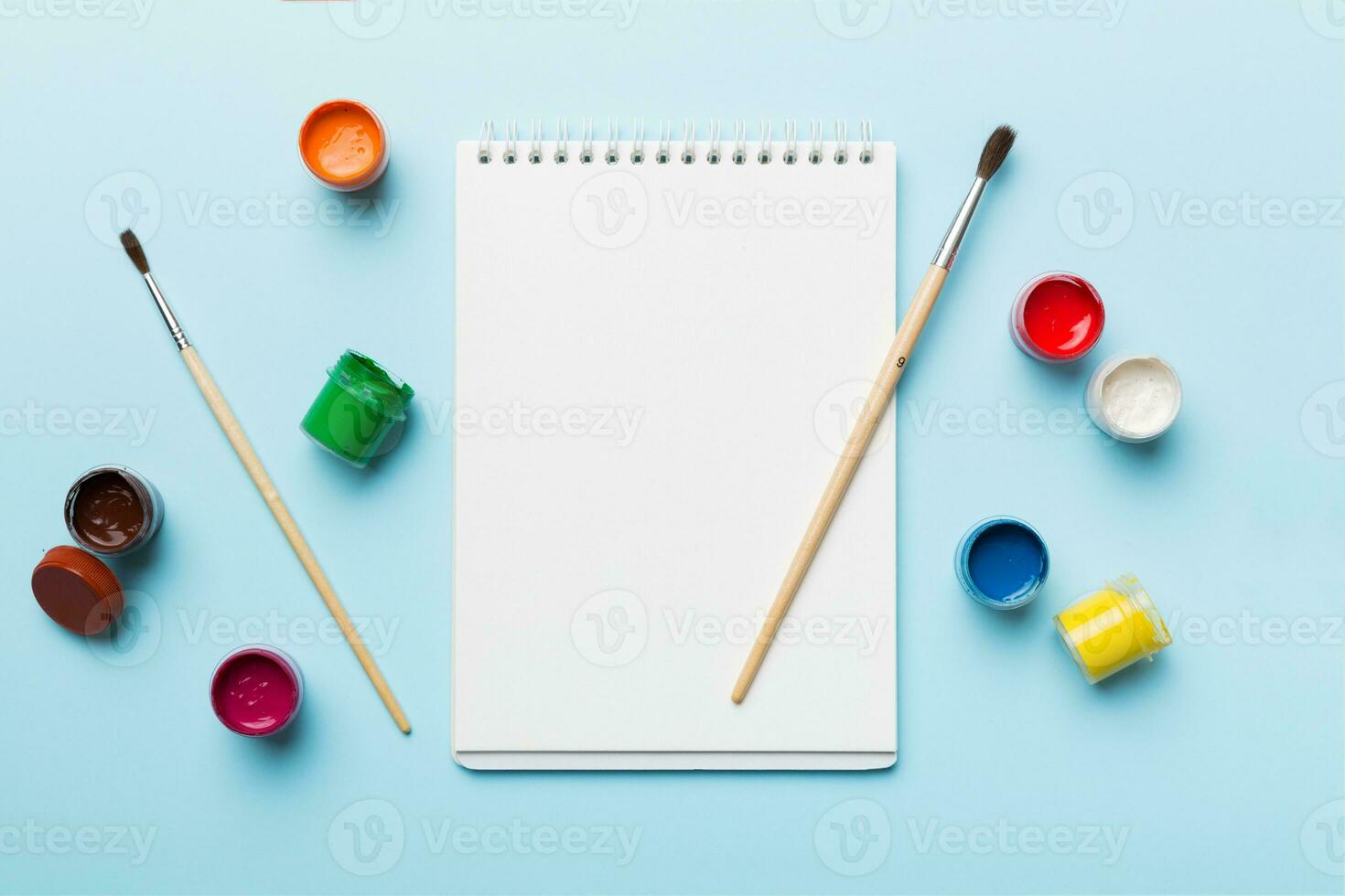 Album pages and paints, pencils, brush on a colored background. Top view with empty space. workplace for creativity. home teaching concept drawing photo