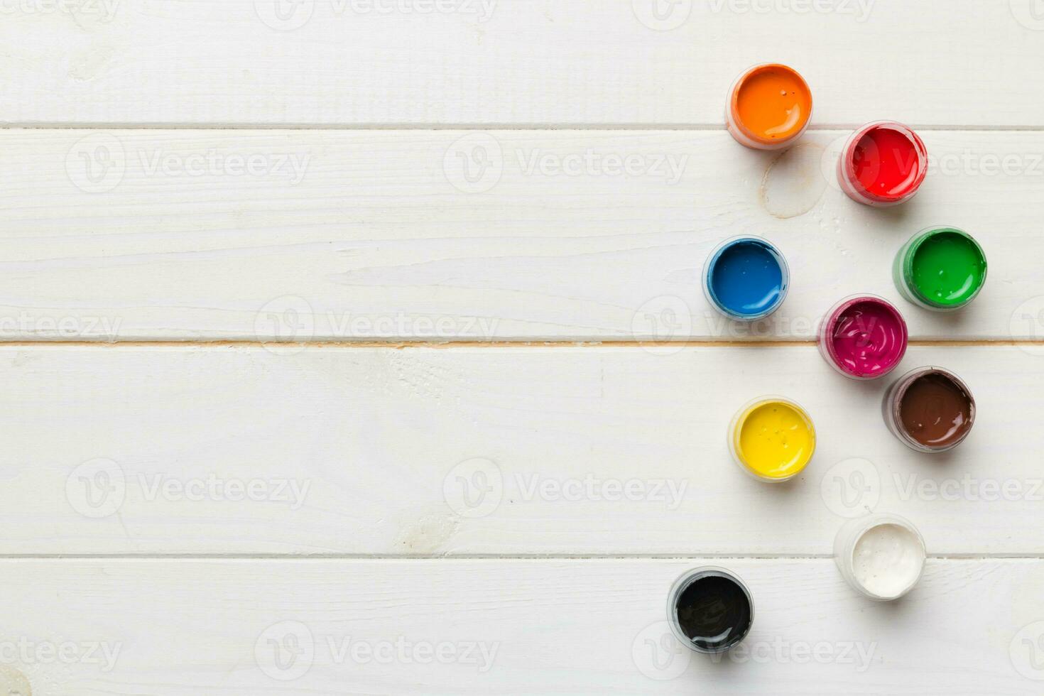 jars with gouache of different colors on Colored background. hobby painting. Top view with empty space. workplace for creativity. home teaching concept drawing photo