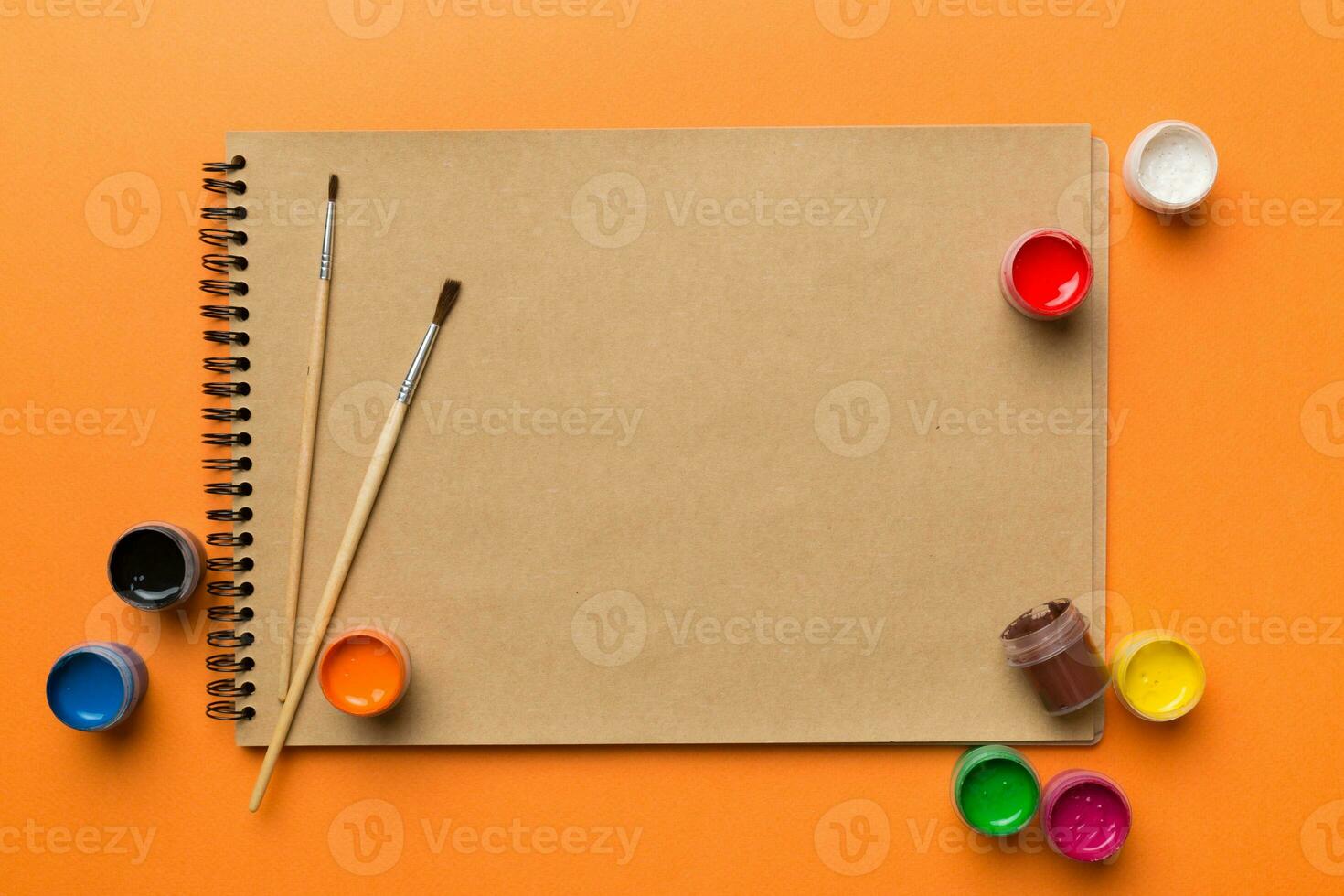 Album pages and paints, pencils, brush on a colored background. Top view with empty space. workplace for creativity. home teaching concept drawing photo