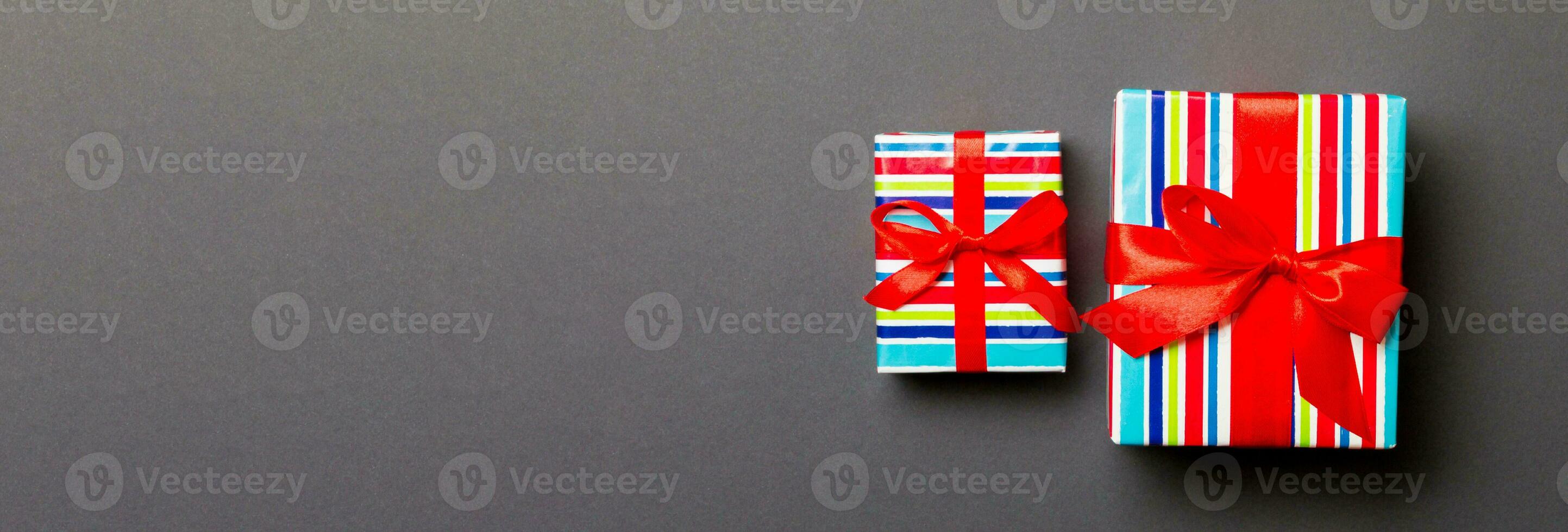 Gift box with red bow for Christmas or New Year day on black background, top view photo