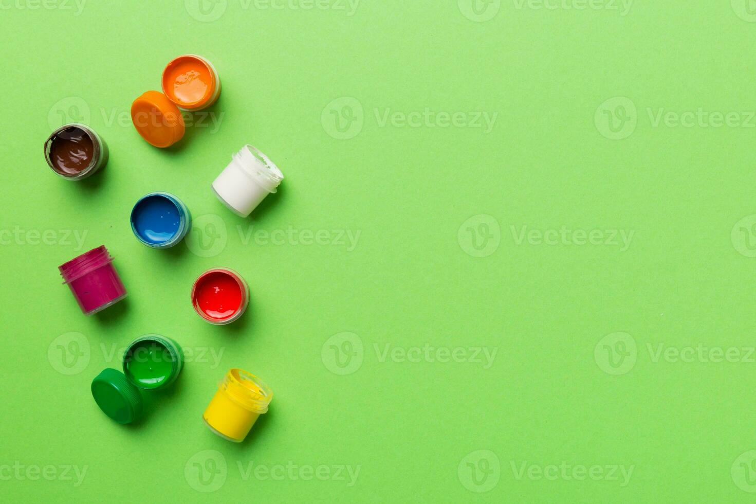 jars with gouache of different colors on Colored background. hobby painting. Top view with empty space. workplace for creativity. home teaching concept drawing photo