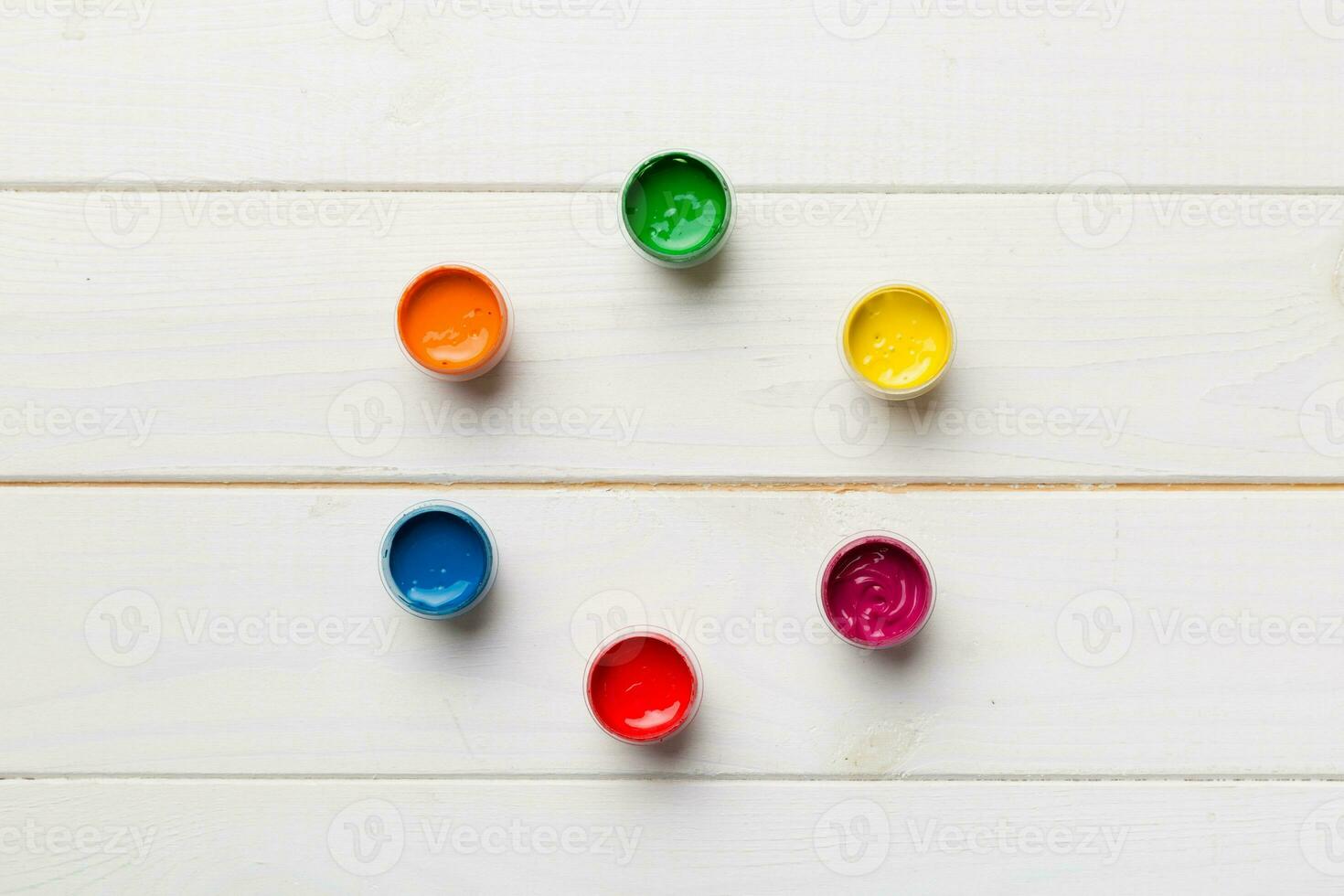 jars with gouache of different colors on Colored background. hobby painting. Top view with empty space. workplace for creativity. home teaching concept drawing photo