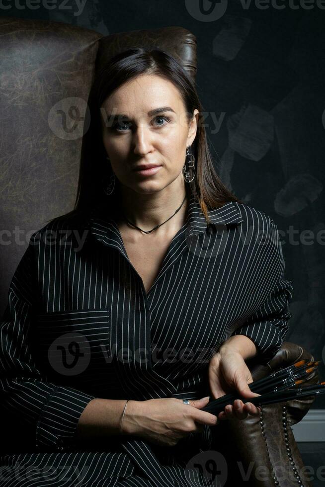 a young brunette female artist stands behind an easel. photo