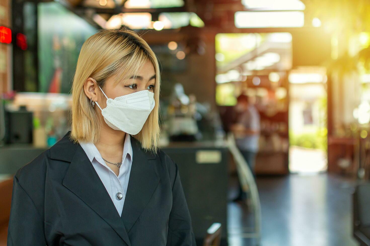 A young woman in a golden-haired suit standing absent-minded in front of a cafe while looking away with copy space. photo