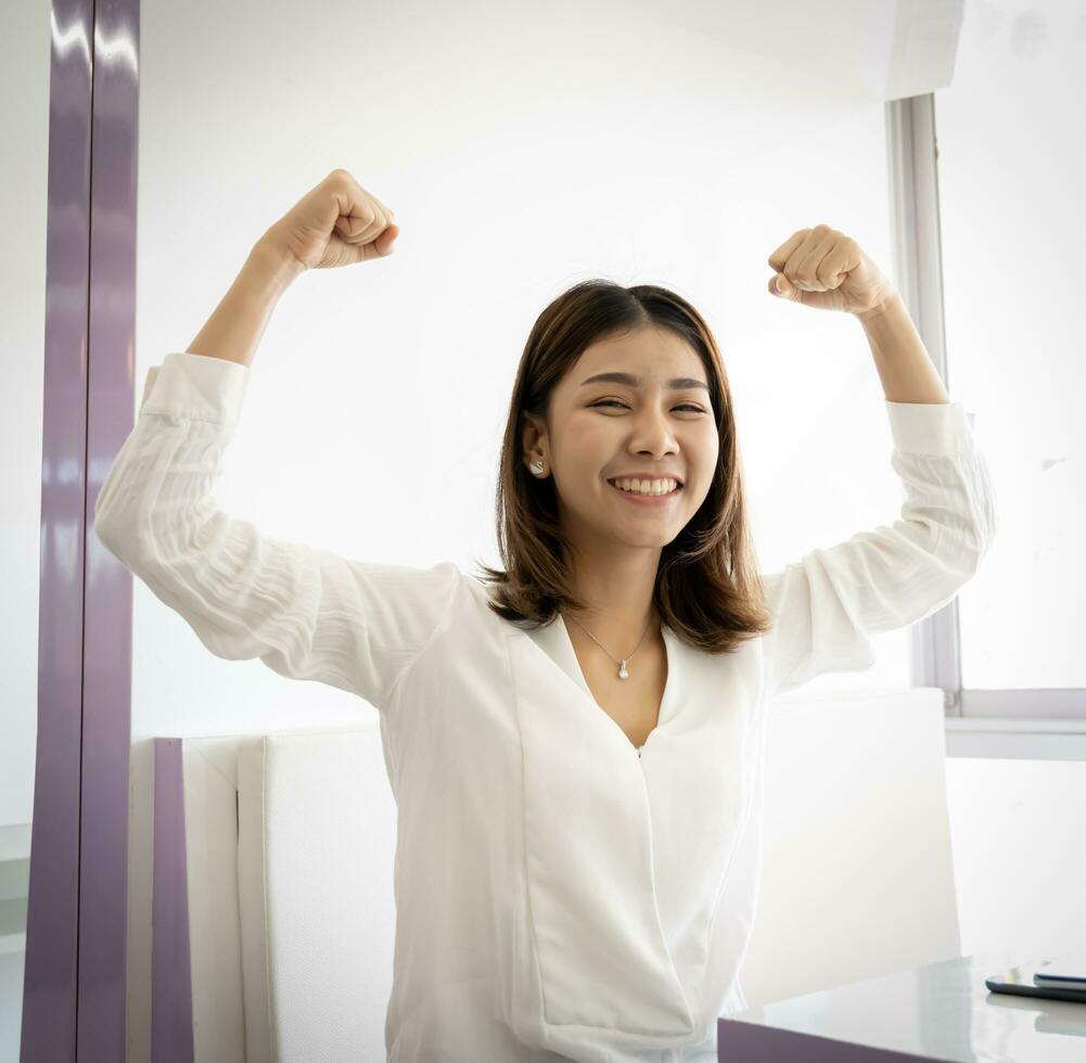 Vertical picture of beautiful businesswoman sitting raised fists victory with smile on her face. photo