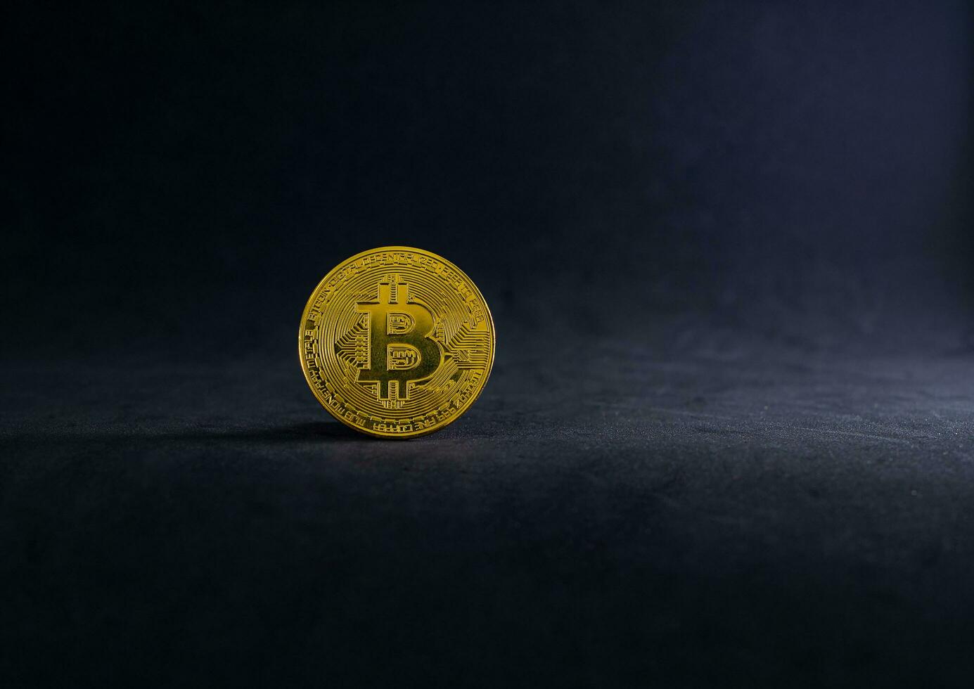 Golden Bitcoin on the floor with black background. Gold digital coin on black with light and shadow. photo