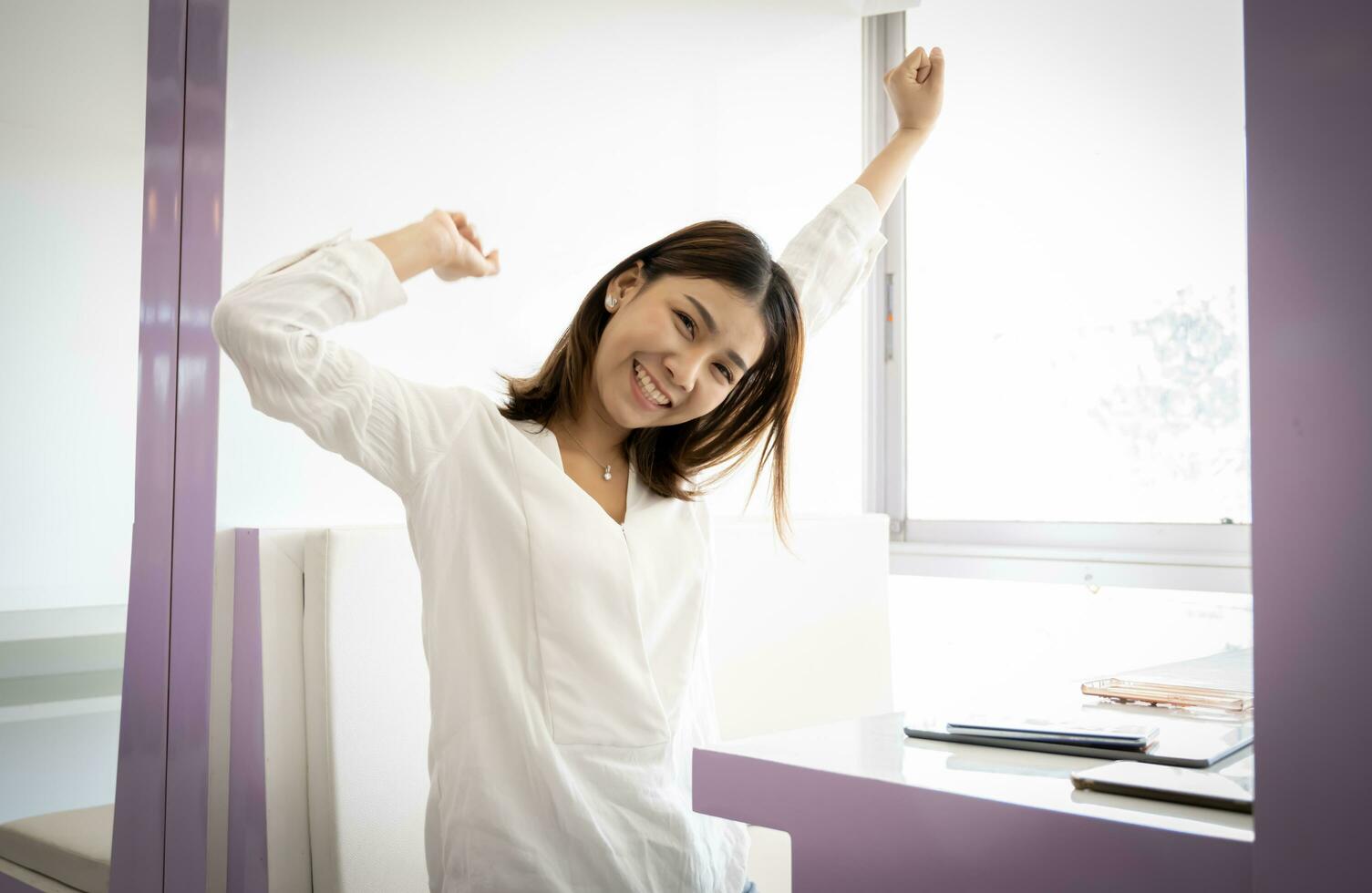 Beautiful asian businesswoman or working lady is stretch themselves or lazily for relaxation on their desk  in her office. photo