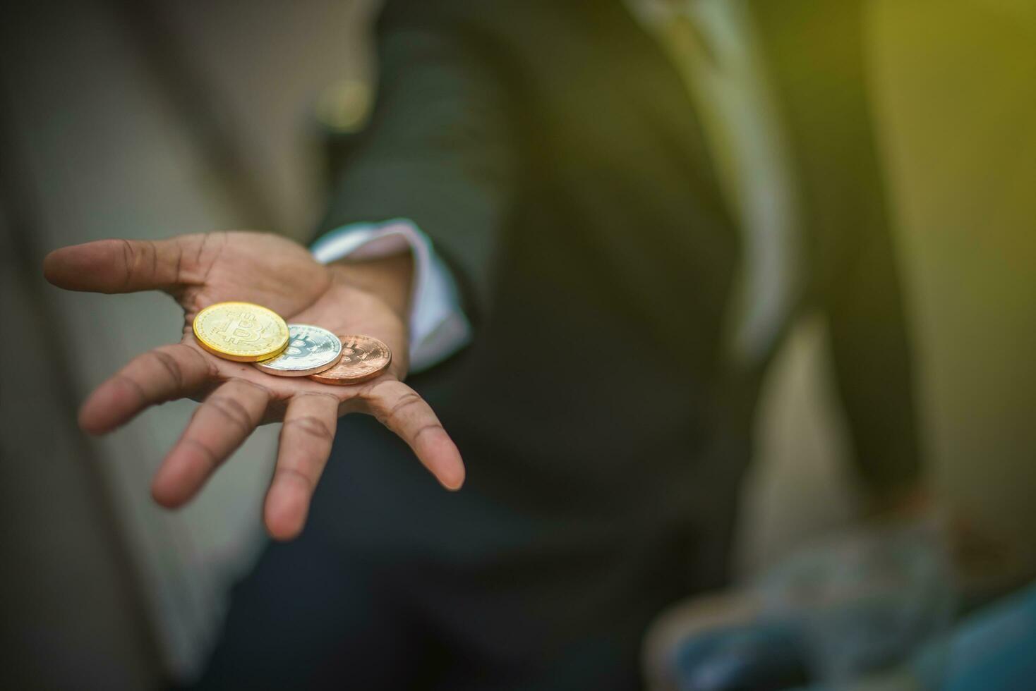 Three Bitcoin on the hand of a young businessman in black suit-Image photo