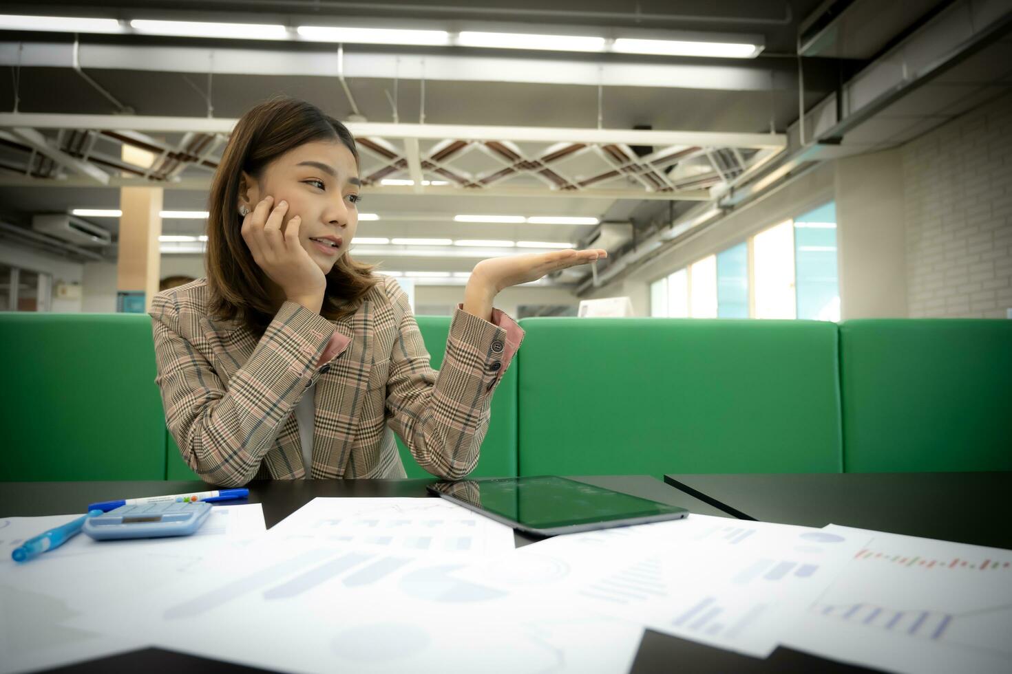Beautiful asian businesswoman looks at the open hand with copy space with an excited expression in her office. photo