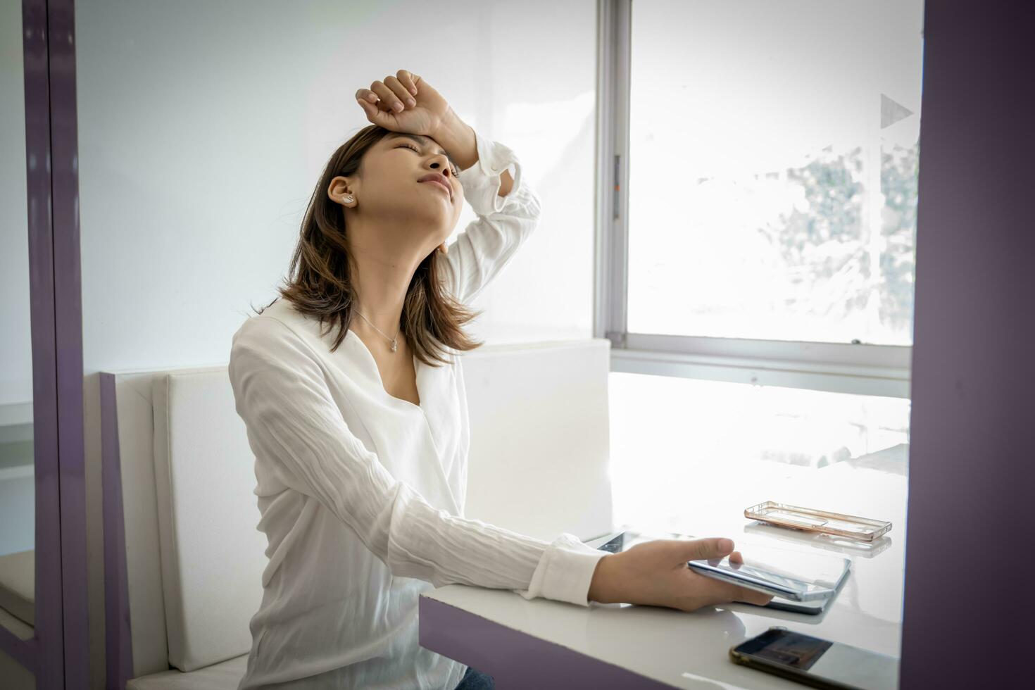 hermosa asiático mujer de negocios es desesperado para un trabajo ella perdido mientras participación su teléfono en su oficina escritorio. foto