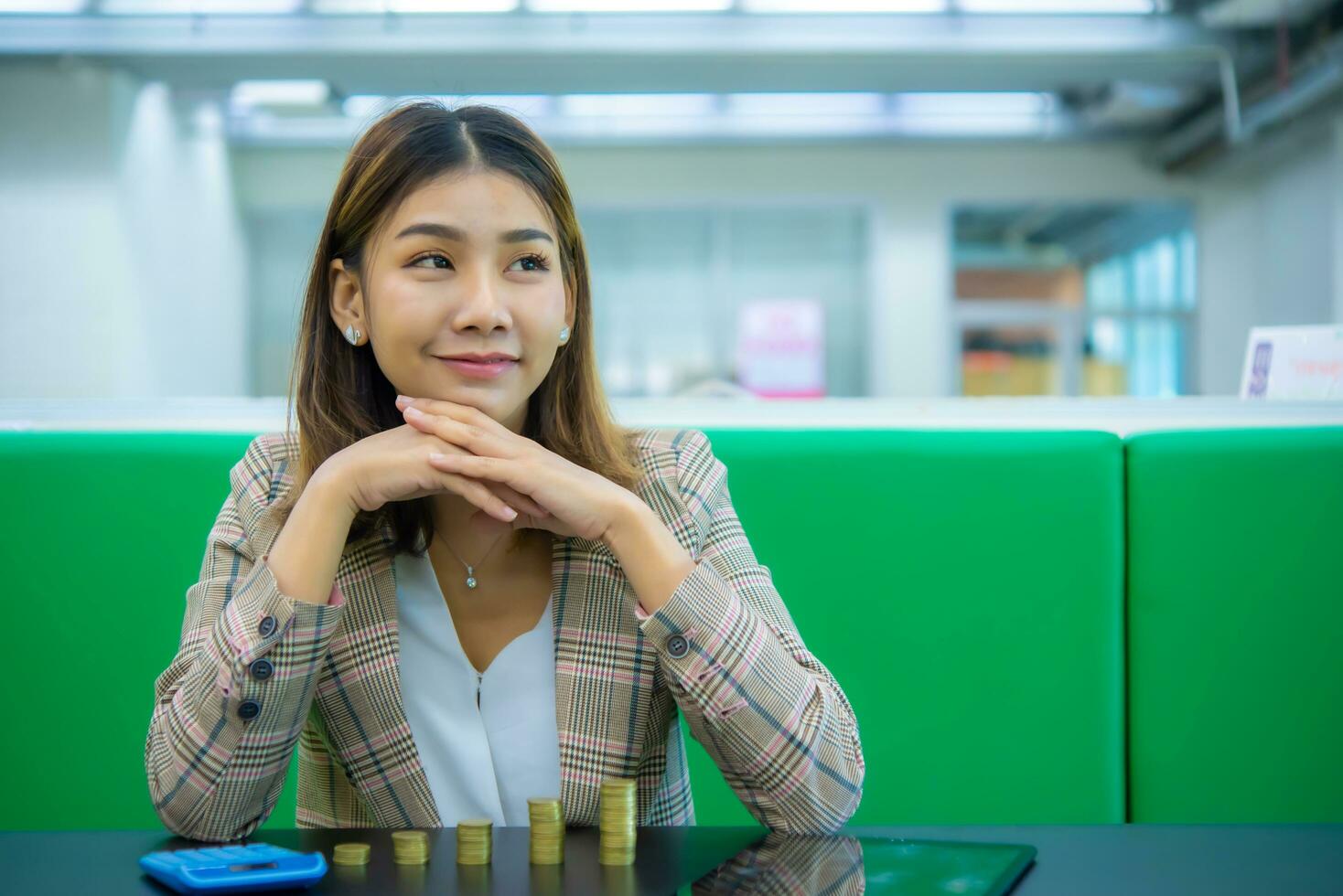 Young beautiful asian business woman is crossing her chin with both hands and looking at the copy space with a smile, Digital marketing. photo