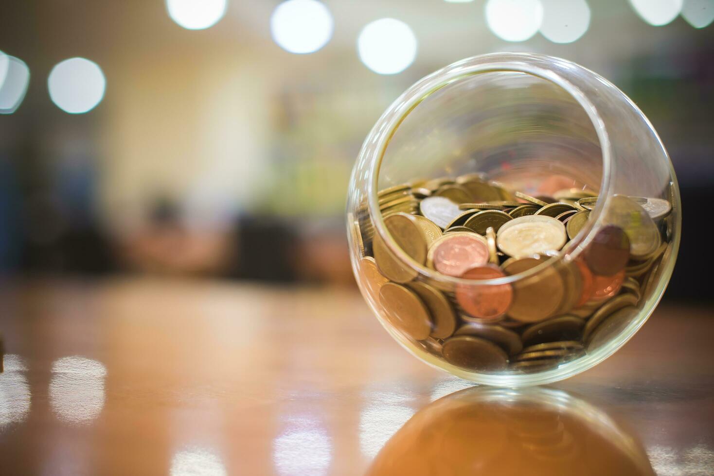 Money coins Thai baht in a round glass jar with Bokeh background. Banking, Finance and Saving money concept. photo