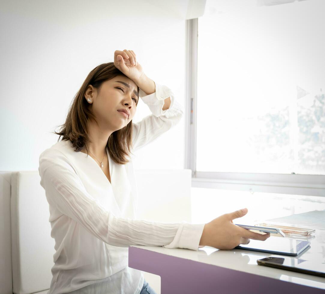 Beautiful asian business woman is tired from work with sad face while sitting in her office. photo