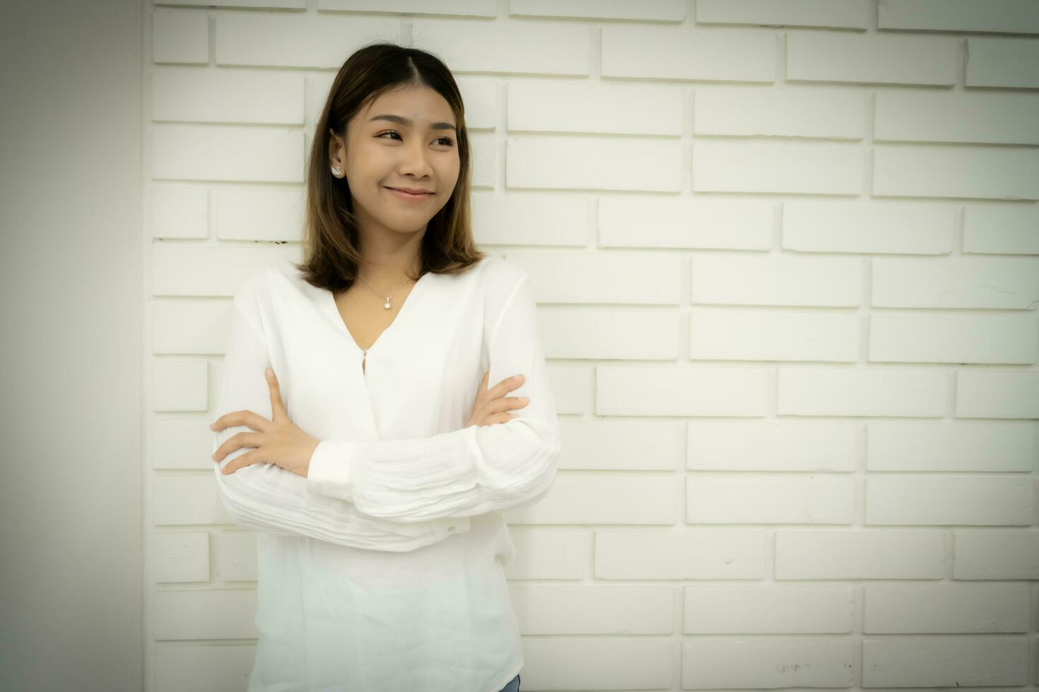 Portrait of a beautiful business woman is standing with arms crossed and looking at the copy space with smile on her face. photo