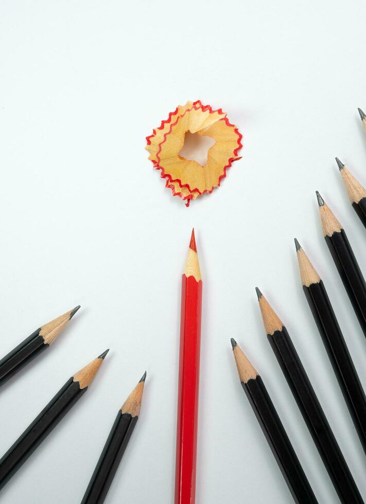 Pencil shavings and Red pencil surround by group of black pencil with white background, Copy space, School and office concept,  Think different and leader concept. photo