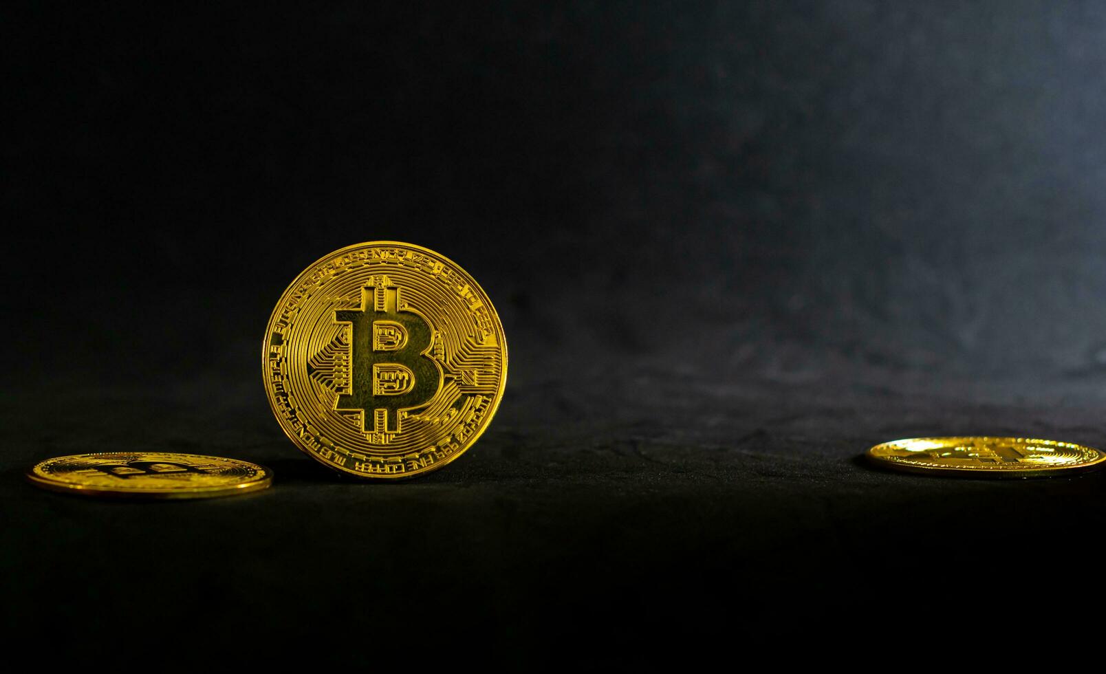 Golden bitcoin, Bitcoin lay on a black table with black background and ray of light. photo
