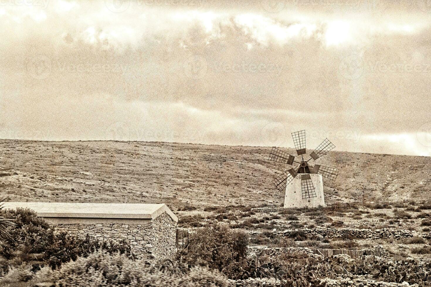 empty mysterious mountainous landscape from the center of the Canary Island Spanish Fuerteventura with a cloudy sky and original windmills photo