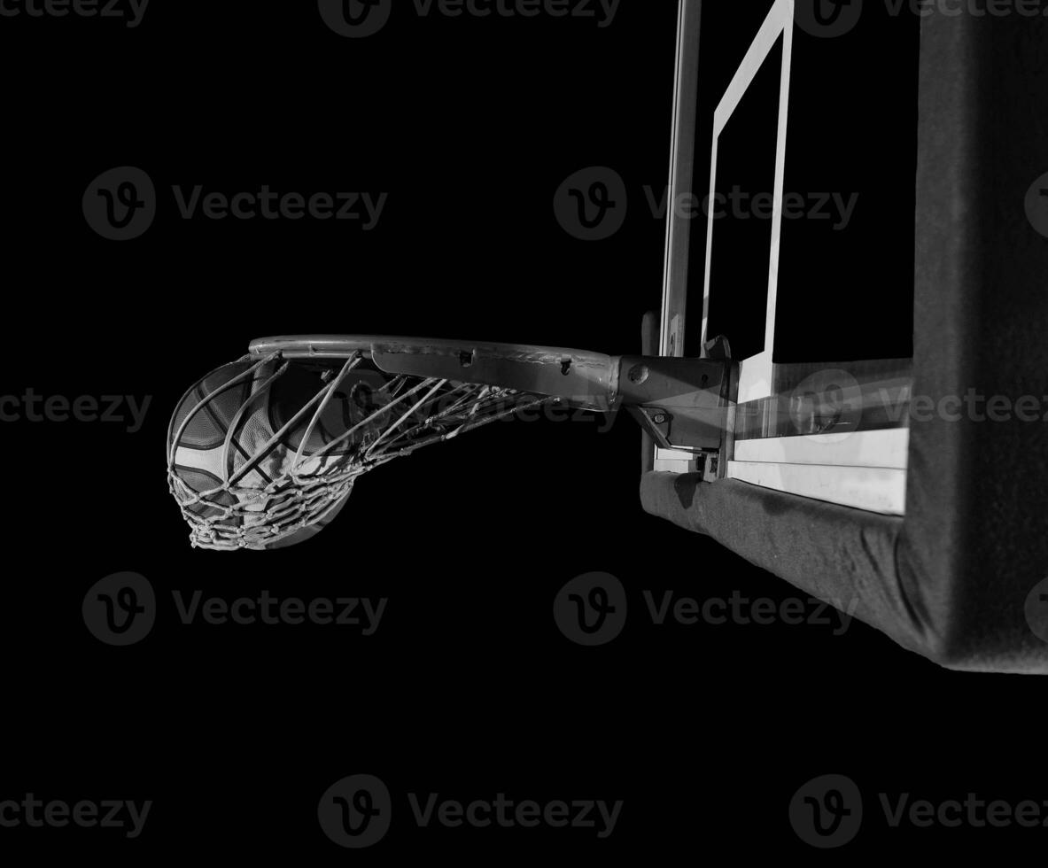 basketball ball falling into the basket on a black background photo