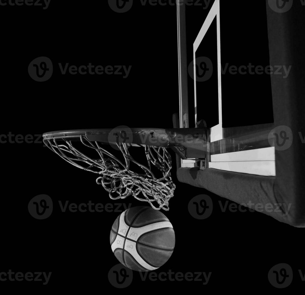baloncesto pelota que cae dentro el cesta en un negro antecedentes foto