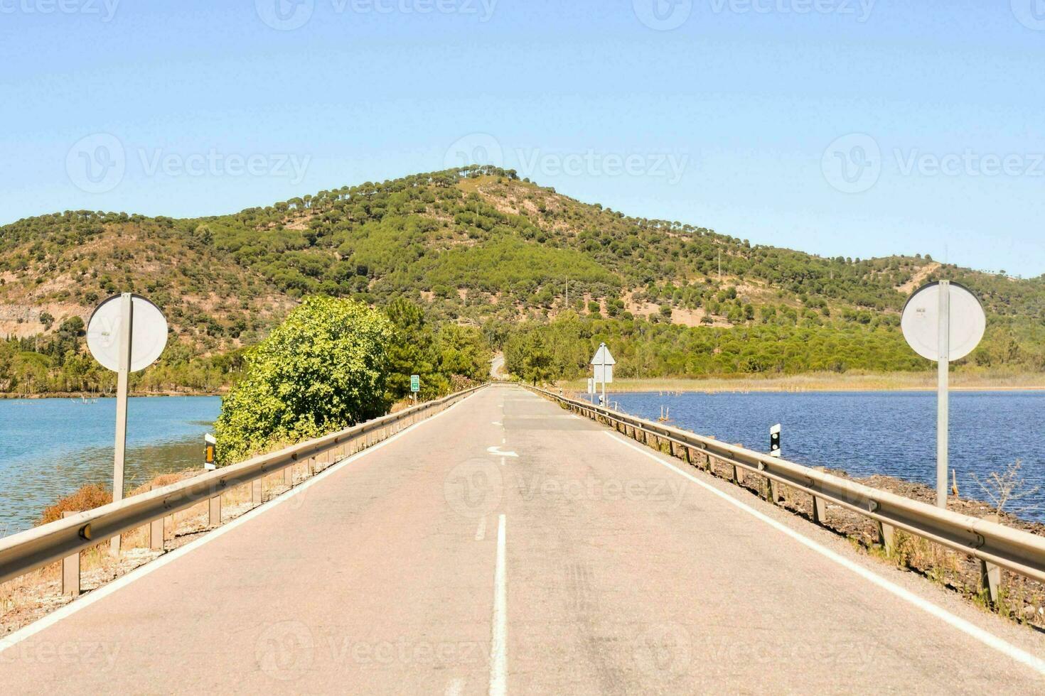 un largo vacío la carretera con un lago en el antecedentes foto