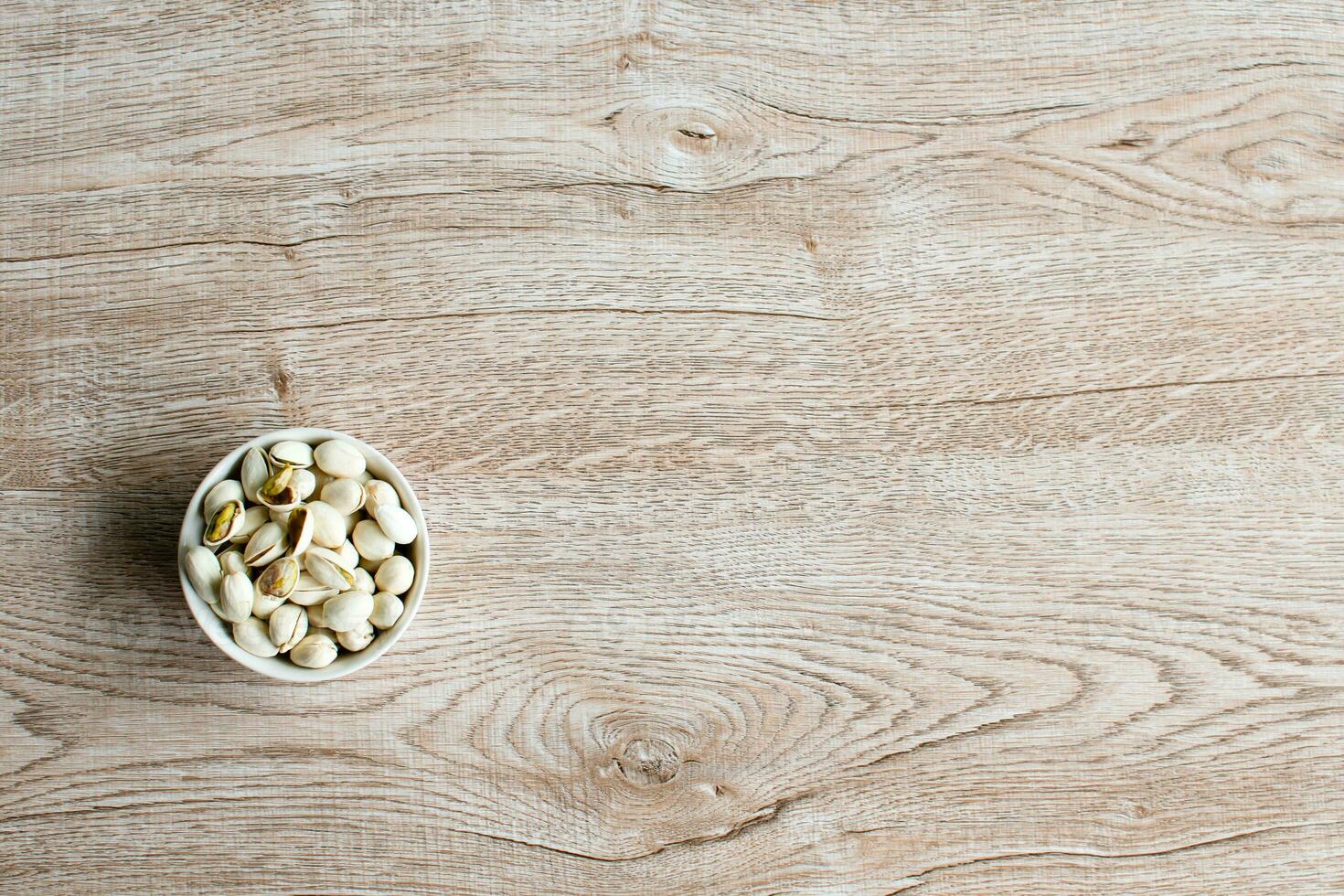 nuts in a cup on an old wood grain table Left corner and take a closeup and top view, has copyspace for text input, the photo is a landscape