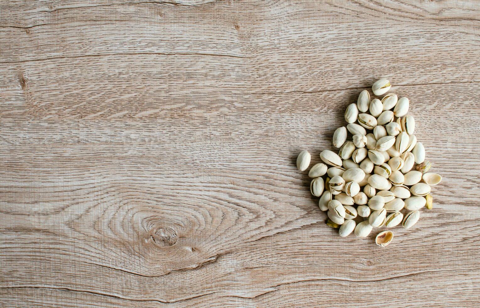 many white nuts on a right old wood grain table corner and take a closeup and top view. left copy space for text input, the photo is a landscape