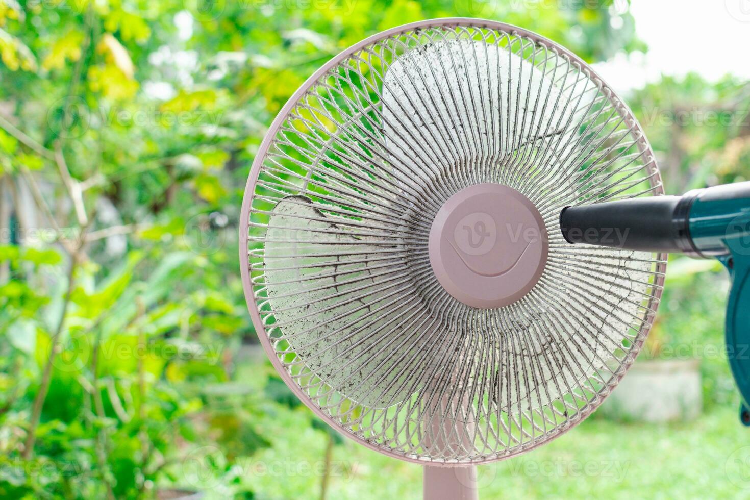 limpieza ventilador escritorio para cuidado de la salud, higiene, y proteccion alergia concepto. el personas limpieza polvo a el ventilador escritorio al aire libre. técnico hombre limpieza de ventilador escritorio con eléctrico soplador. foto