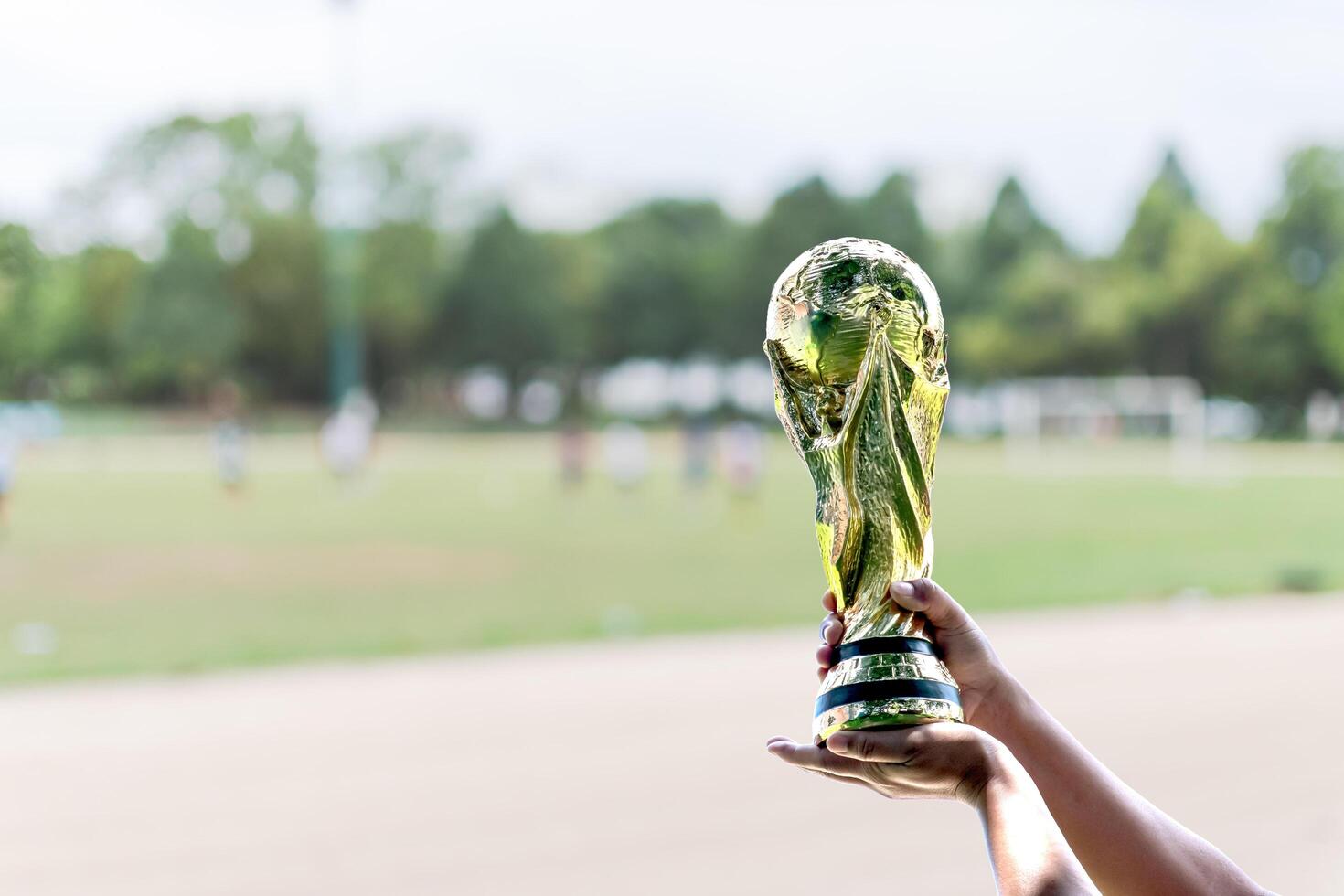 World Cup with blurred background. hand holding a World Cup winner trophy. The concept for World Cup in Qatar. Copy space on left for design or text photo