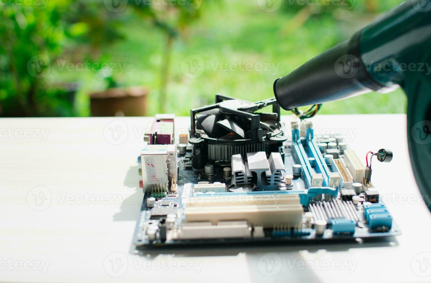 maintenance mainboard or motherboard concept. engineer cleaning a mainboard or motherboard hardware computer desktop or pc outdoor. technical cleaning of motherboard or mainboard with Electric Blower photo