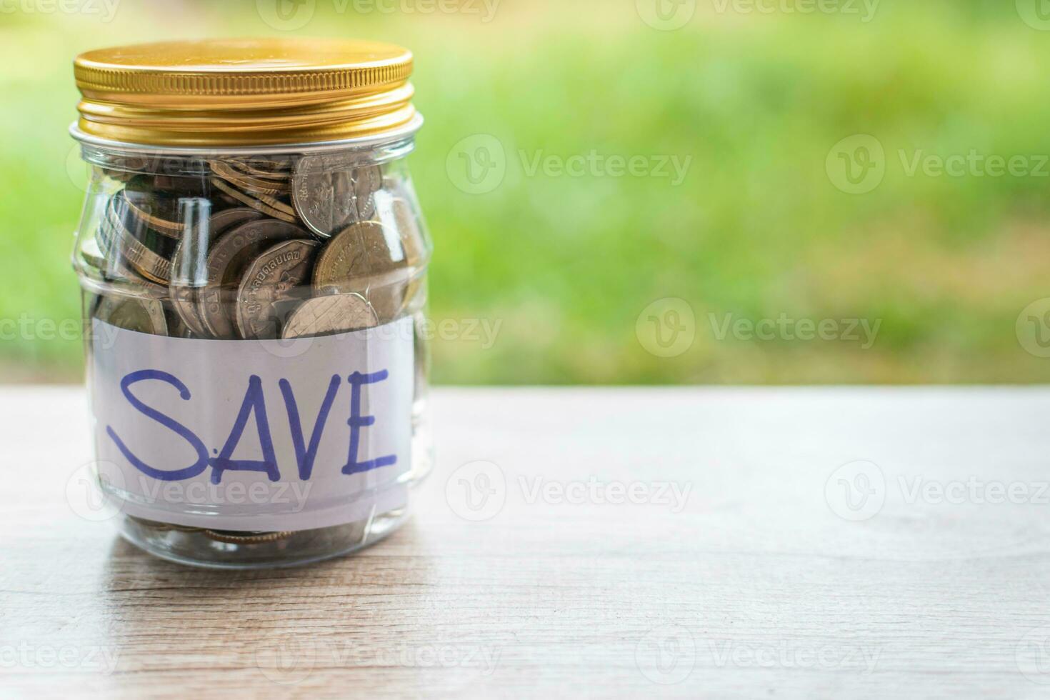 Coins and text SAVE in a glass jar placed on a wooden table. Concept of saving money for investment and emergency situations. Close up, Blurred background photo