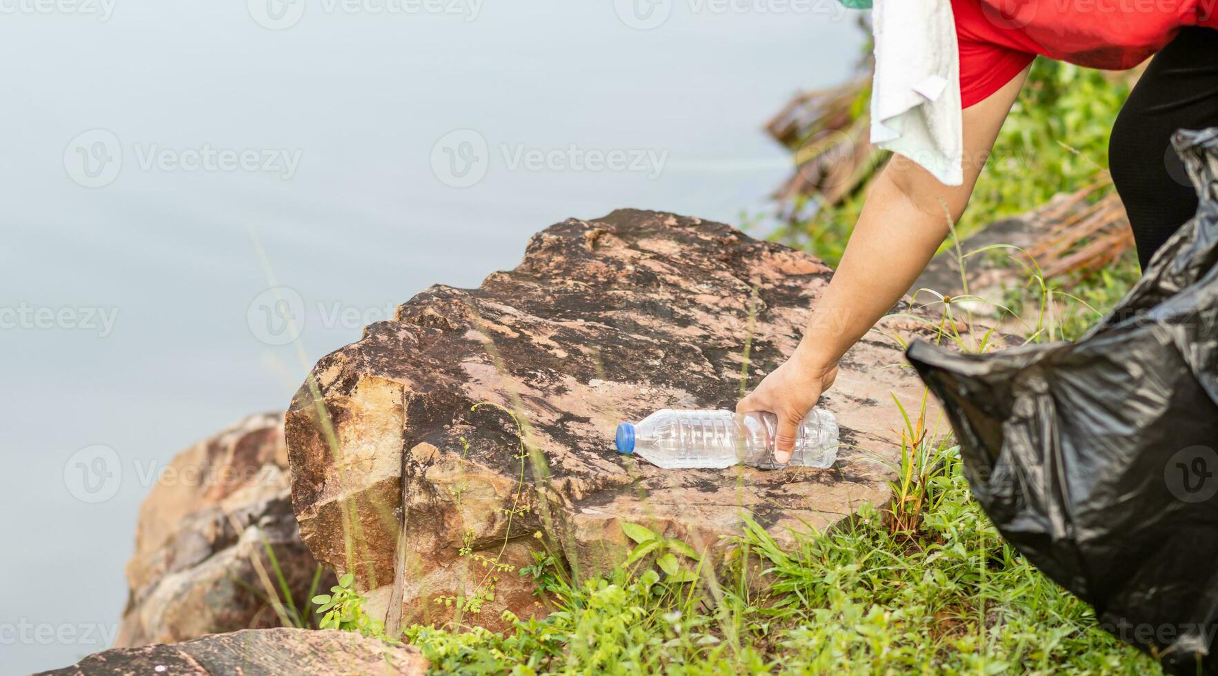 A woman cleans up by picking up plastic bottles at a natural water reservoir. Concept of protecting the environment, saving the world, recycling, reducing global warming. close up, blurred background photo