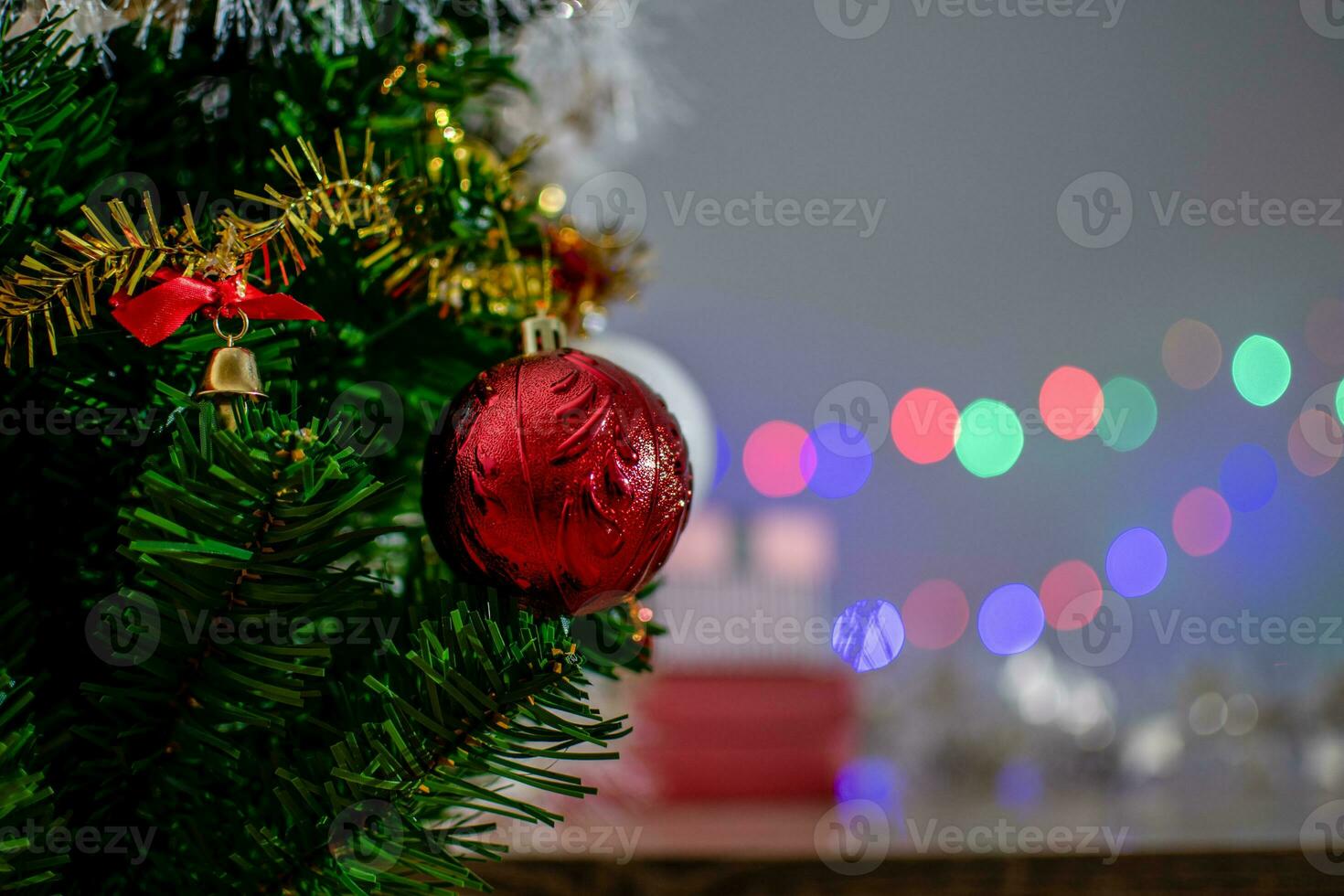Closeup, green Christmas tree decorated with a medium red ball and has beautiful bokeh. Copy space for design and text, blurred background photo