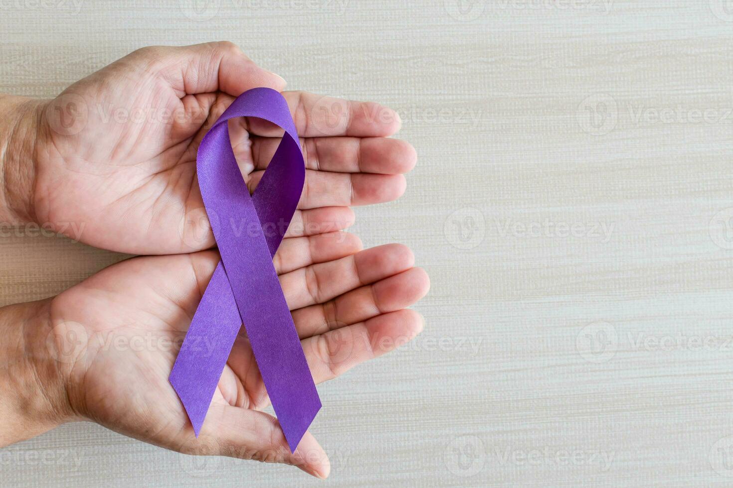 International Overdose Awareness Day, hand holds purple awareness ribbon on wooden table, a concept for World Lupus Day, Autoimmune disease, Immune System Disorders, May Lupus Awareness Month, photo