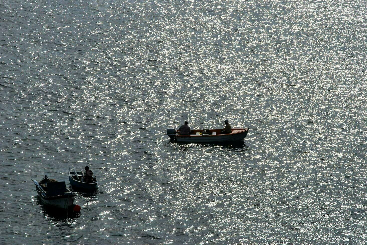 three small boats in the water with the sun shining on it photo