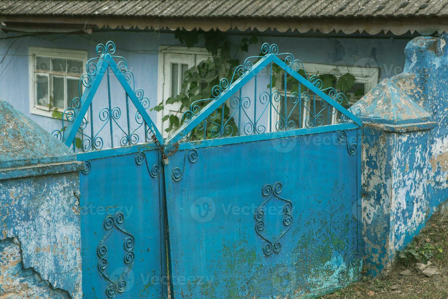 The gate to the house is decorated with a pattern of metal. Old abandoned house in the village Old iron gate in the yard of a country house. Green metal gate. photo