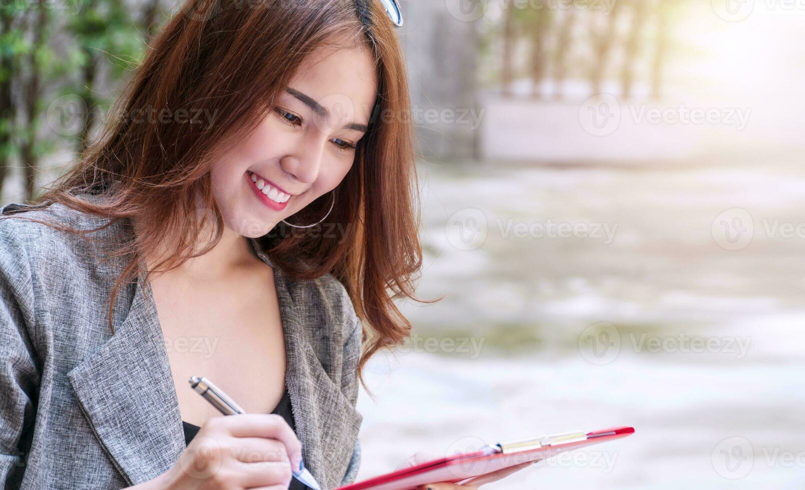 Charming young woman smiling look like thinking about something to use her idea with copy space. Attractive business woman sitting in coffee shop smile and thinking looking to the side with pen. photo