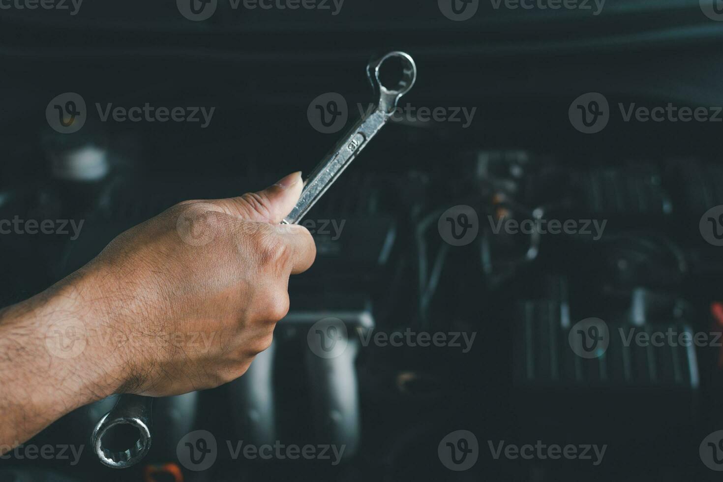 Concept of engine maintenance Mechanic holds a wrench to tighten the nut in engine repair. Engineers are examining the combustion system. Closeup. Selective focus. Blurred background. photo