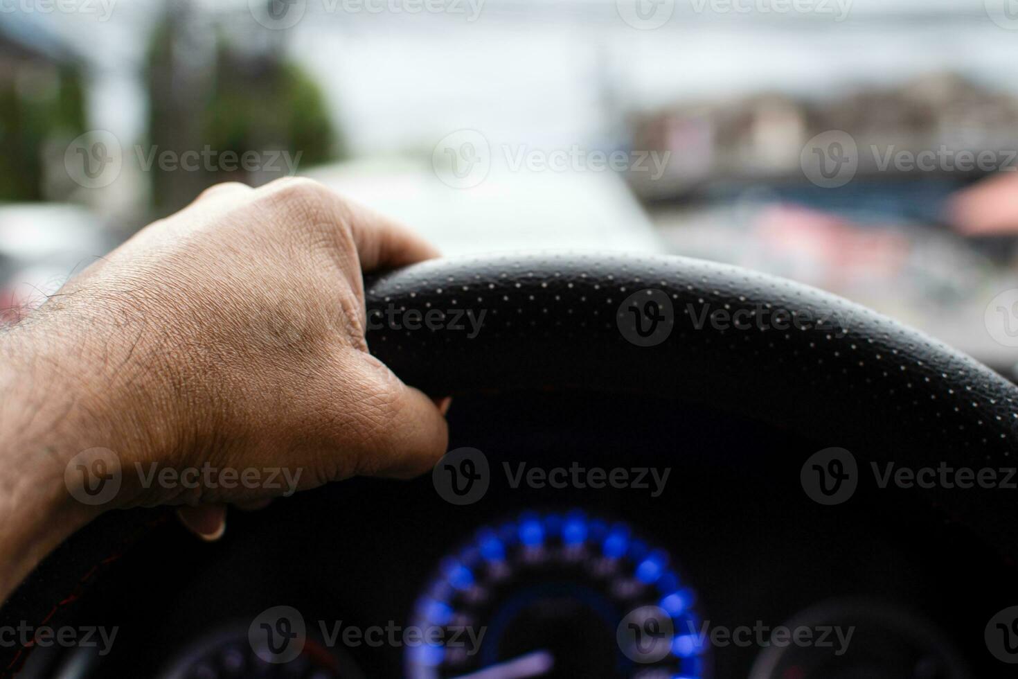 A man driving a left hand to hold the steering wheel To control the car carefully While traffic congestion, has copyspace on top for input text, take a close-up shot, blurred background photo