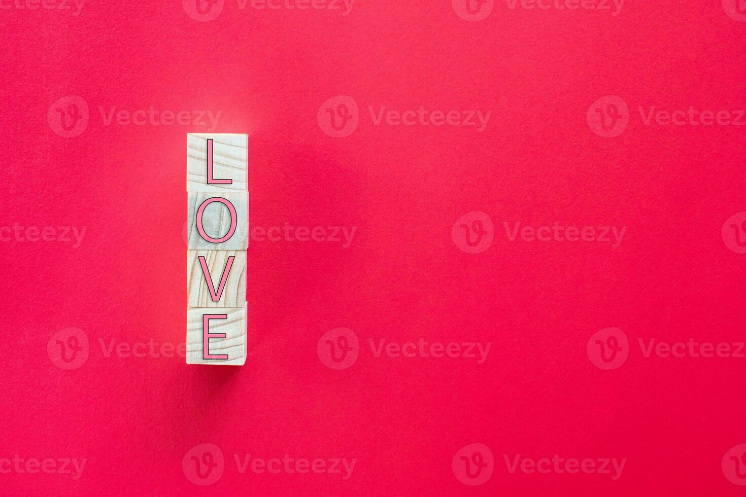 Take a close-up shot. The LOVE letters on the wooden cube are arranged vertically on a red background. Concept of Love Day or Valentine Day photo