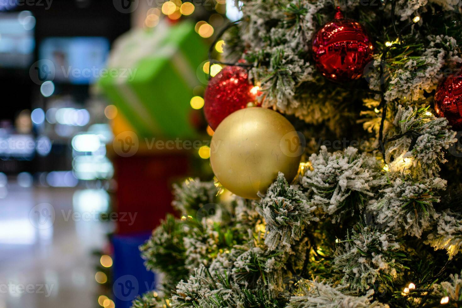 Close up medium golden balls Christmas tree decorated with small bulbs is beautiful. Christmas tree decoration with white snow, copy space on left for design or text, blur background, beautiful bokeh. photo