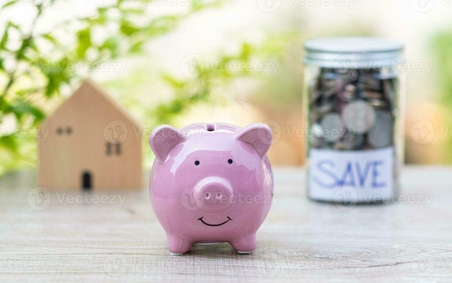 pink pig piggy bank on wood table, concept, business, finance, banking, saving, real estate, investment. nobody, no people, blur Model wooden house, and background photo