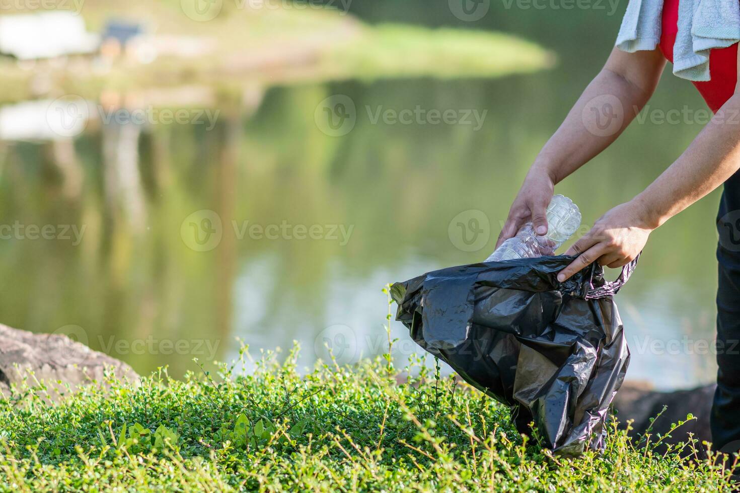 Woman cleans up by picking up plastic bottles at a natural water reservoir. Concept of protecting environment, saving world, recycling, reducing global warming, Earth Day. close up, blurred background photo