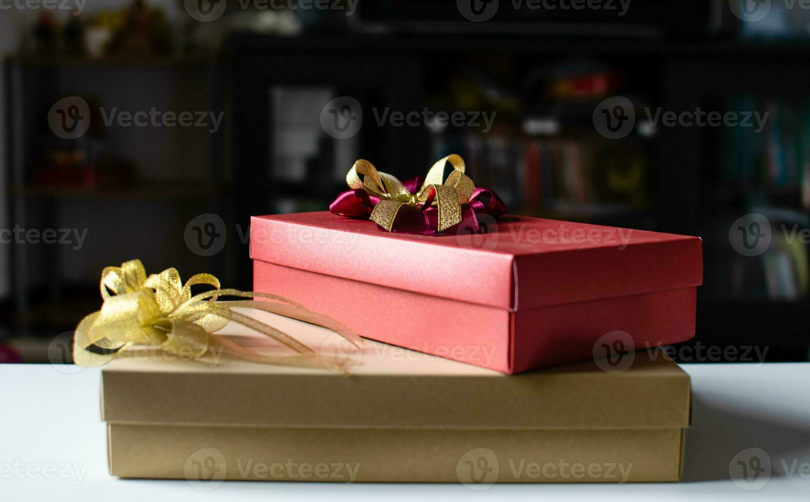 The red and gold color Presents celebrate box with red and gold ribbons placed on a white table with copy space on the right can input text, take close-up photography, and top view, blurred background photo